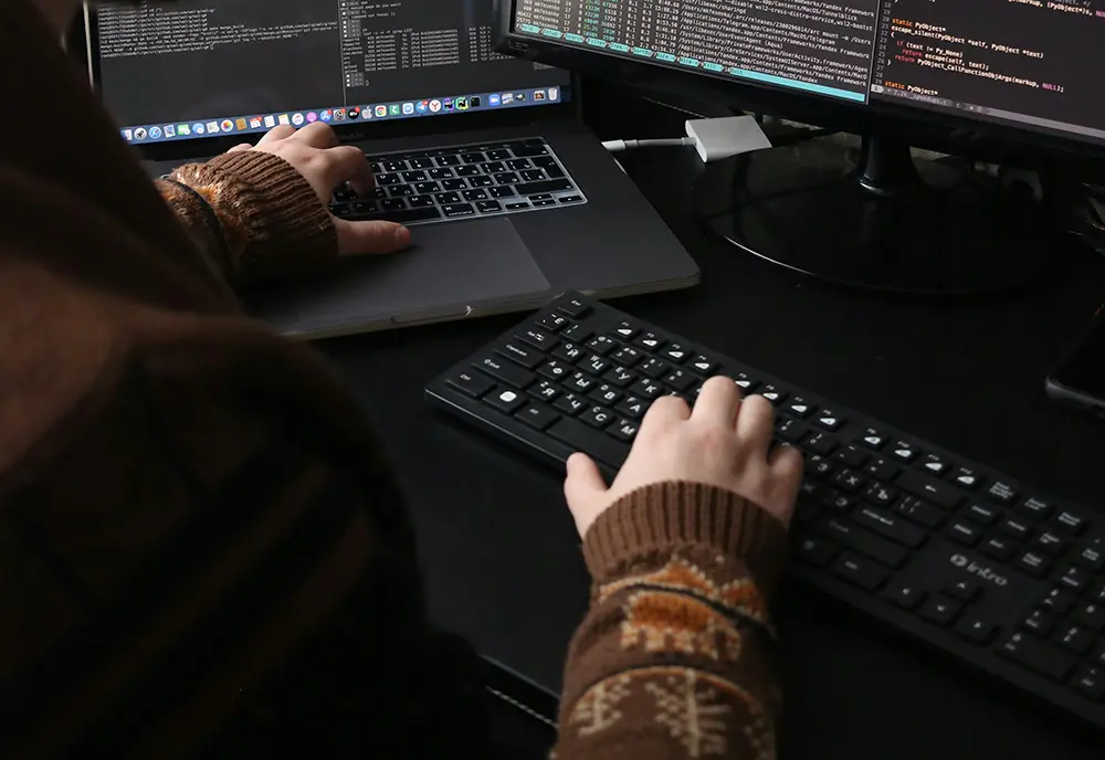 Eine Person sitzt am Computer und tippt auf der Tastatur